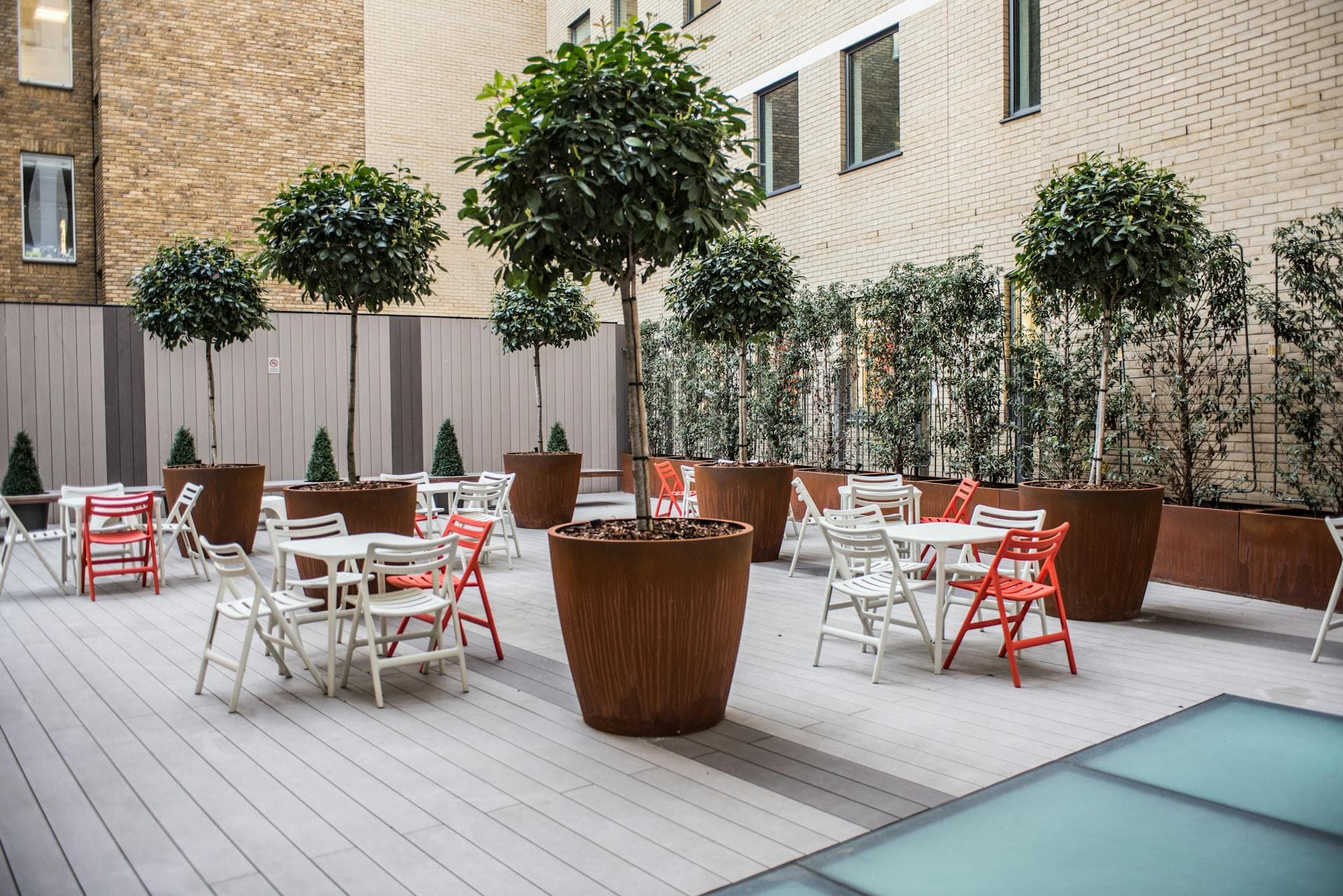 Row of LEAFO planters in varied finishes and plants against a sage-green slatted wall