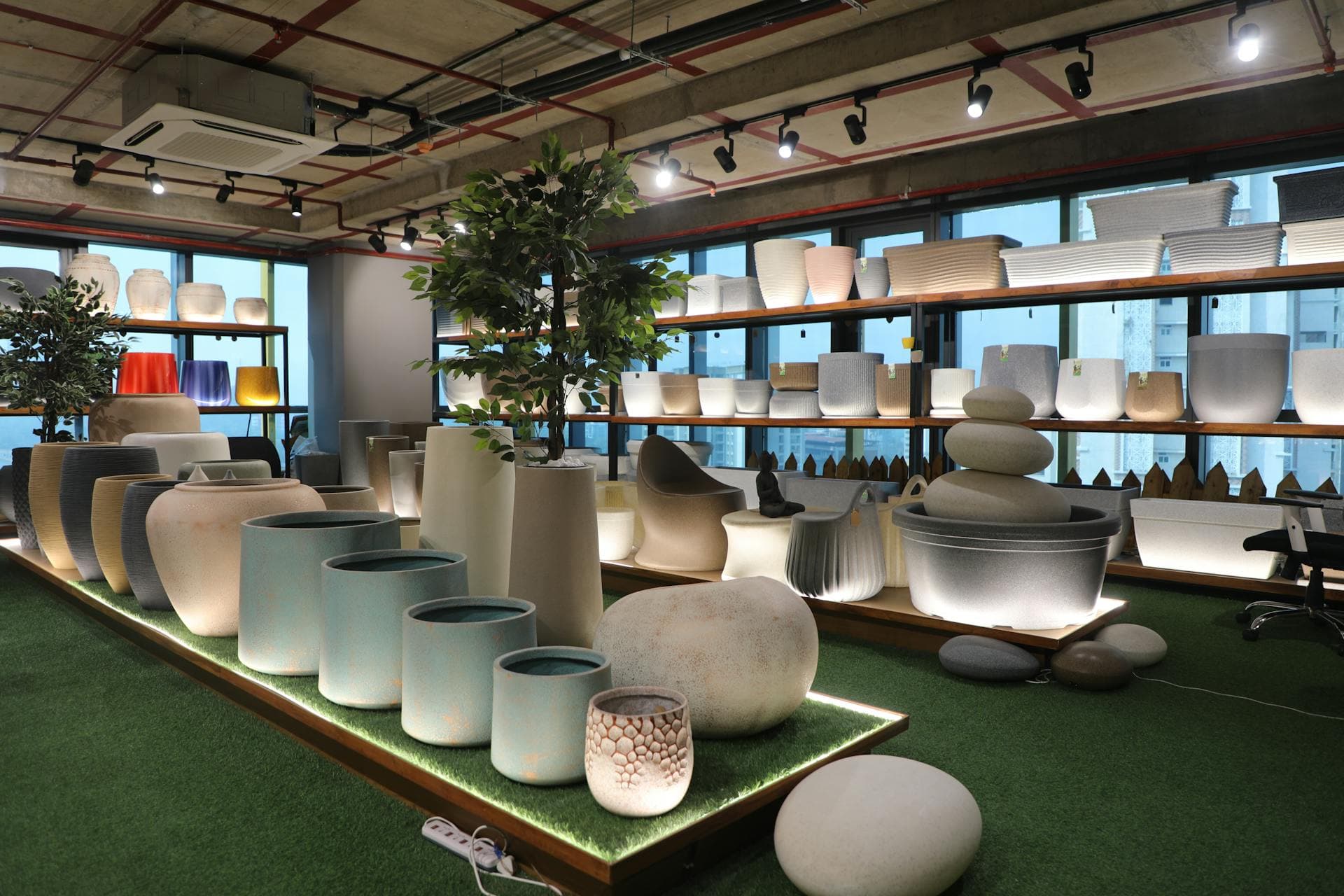 LEAFO showroom with planters of many shapes and sizes on turf and shelving, city skyline through windows